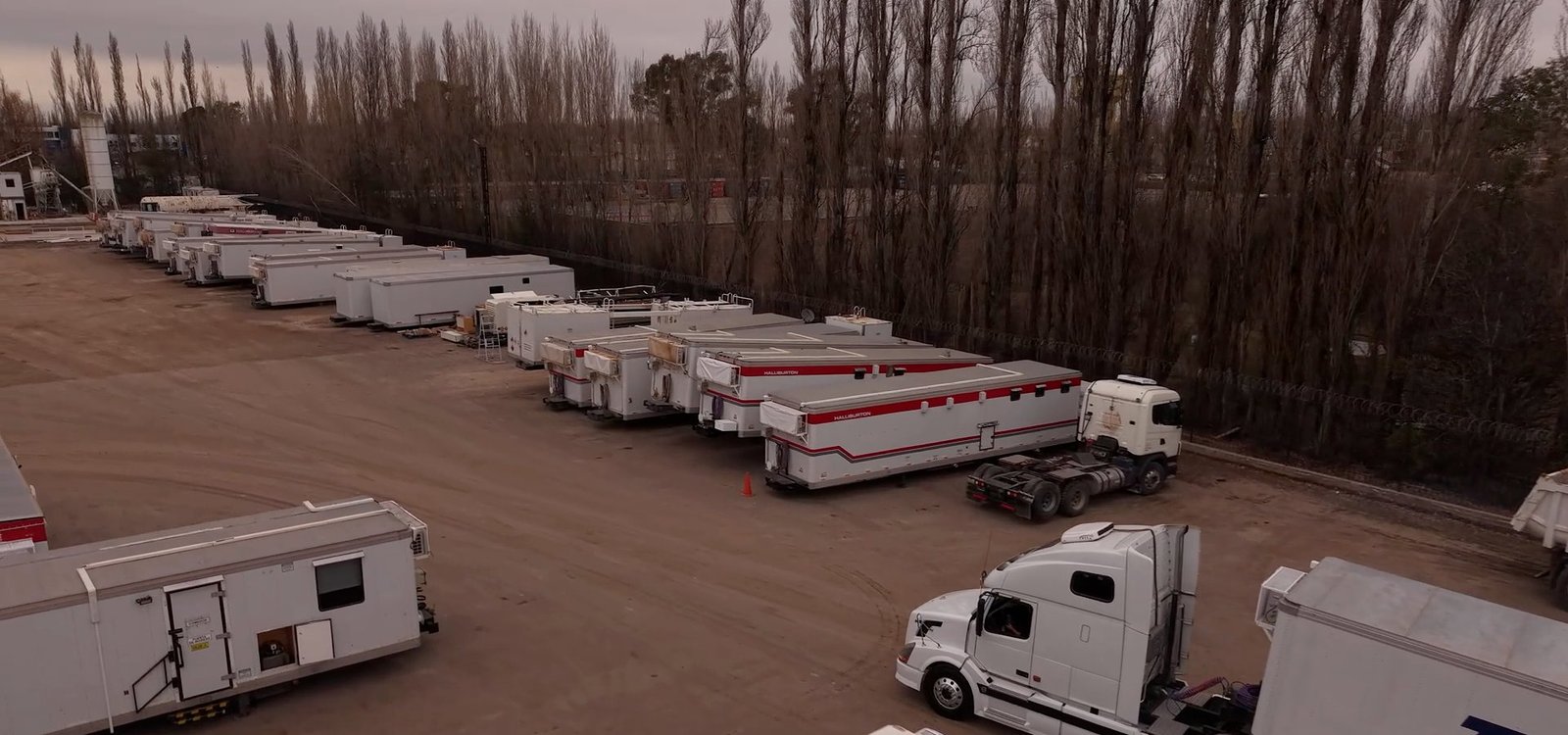 Vista aérea de la base operativa del grupo FAMACRI con trailers habitacionales y camiones en Cipolletti